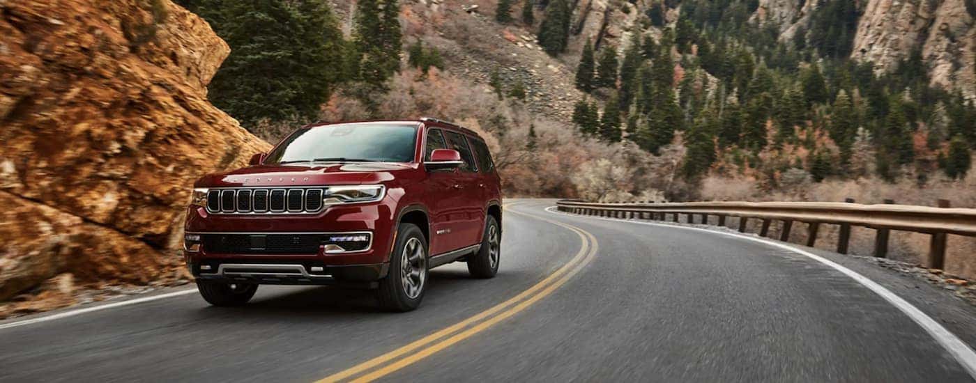 A red 2022 Wagoneer is shown from the front driving on an open road after leaving a California Wagoneer dealer.