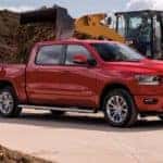 A red 2021 Ram 1500 is being used at a construction site to haul mulch.