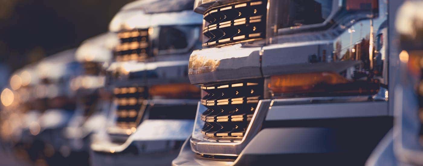 The grilles of trucks in a line at a used truck dealership are shown.