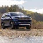A blue 2022 Wagoneer is parked on a riverbank.
