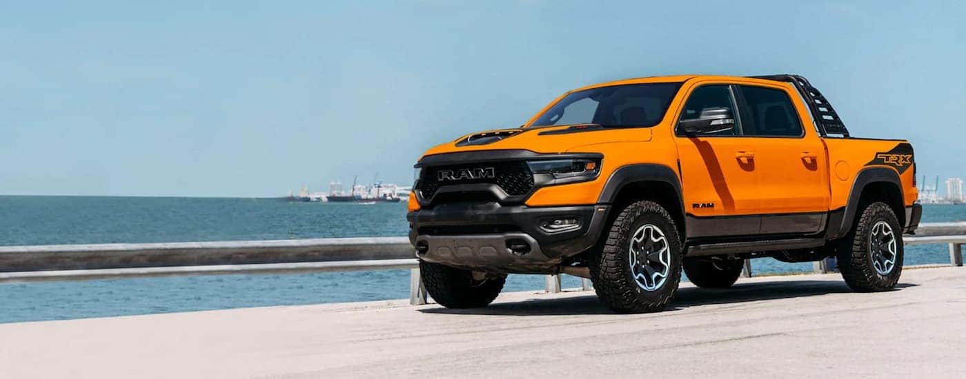 An orange 2022 Ram 1500 TRX Ignition Edition is shown parked near the ocean.