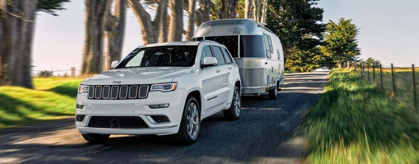 A white 2020 Jeep Grand Cherokee is shown from the front towing an Airstream.