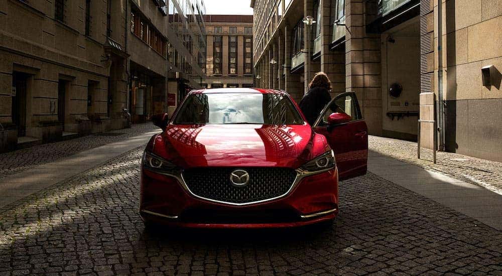 A red 2020 Mazda 6 is shown from the front parked on a brick street.