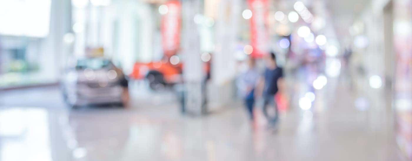 A blurred showroom shows used cars for sale.