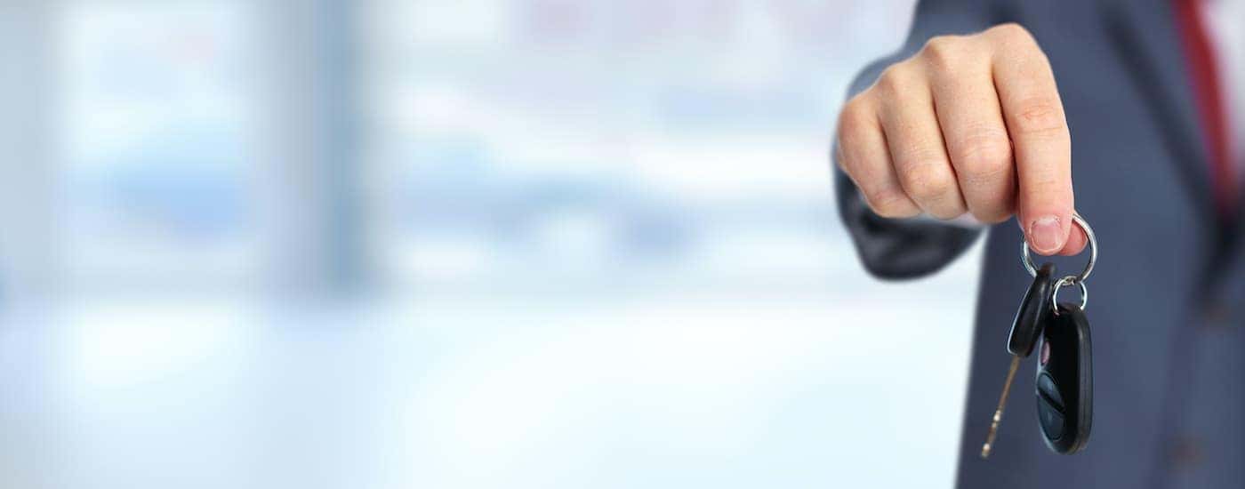 A man is holding out a set of car keys. 