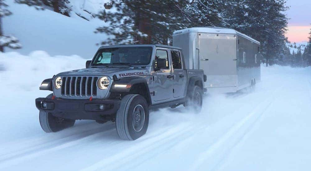 A grey 2021 Jeep Gladiator is towing a closed trailer.