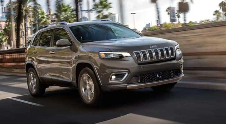 A silver 2021 Jeep Cherokee is driving down a road after searching new Jeeps for sale.