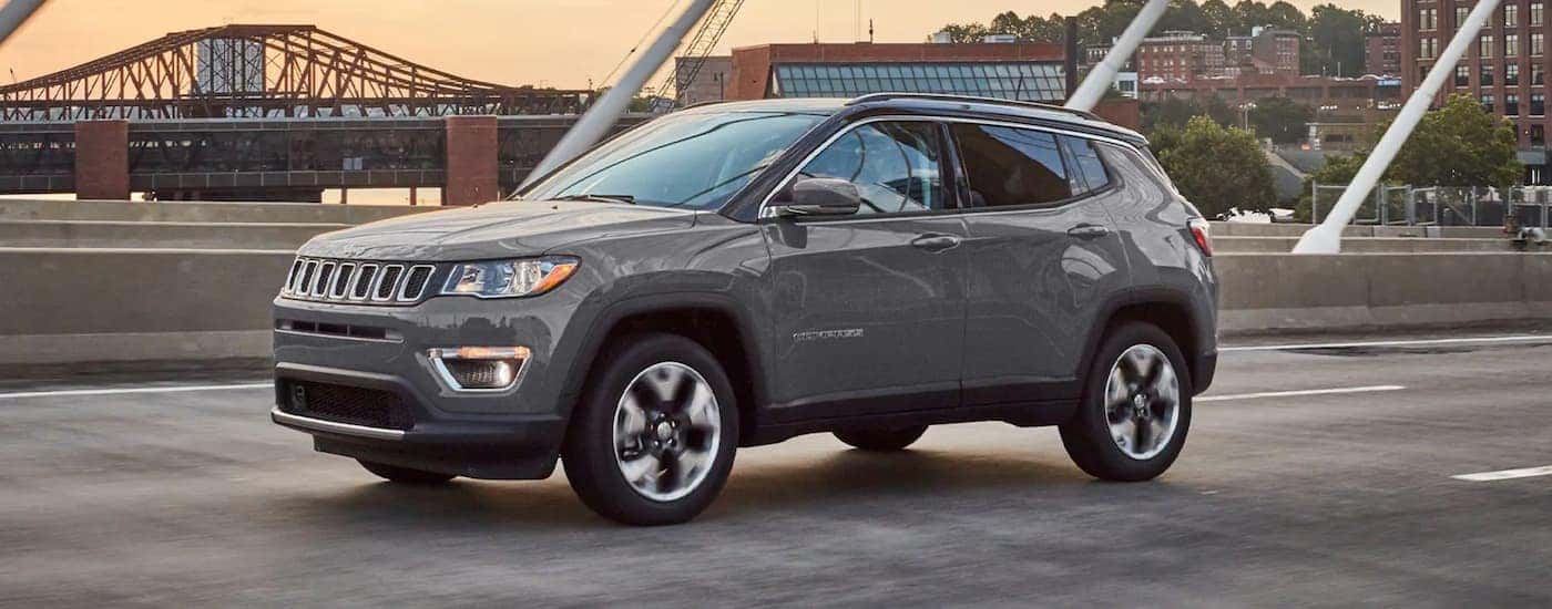 A grey 2021 Jeep Compass is shown driving over a bridge.