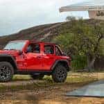 A red 2021 Jeep Wrangler 4xe is shown parked at a charging station.