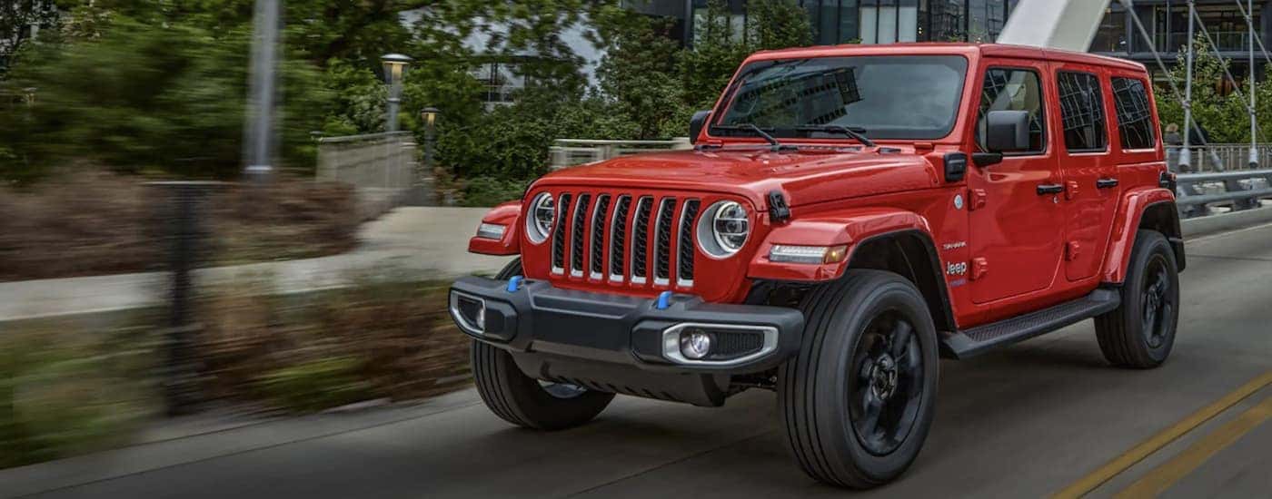 A red 2022 Jeep Wrangler 4xe is shown from the front driving on an open road.