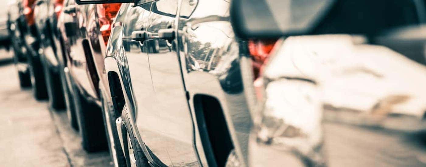 A close up of a line of trucks is shown at a used car lot.