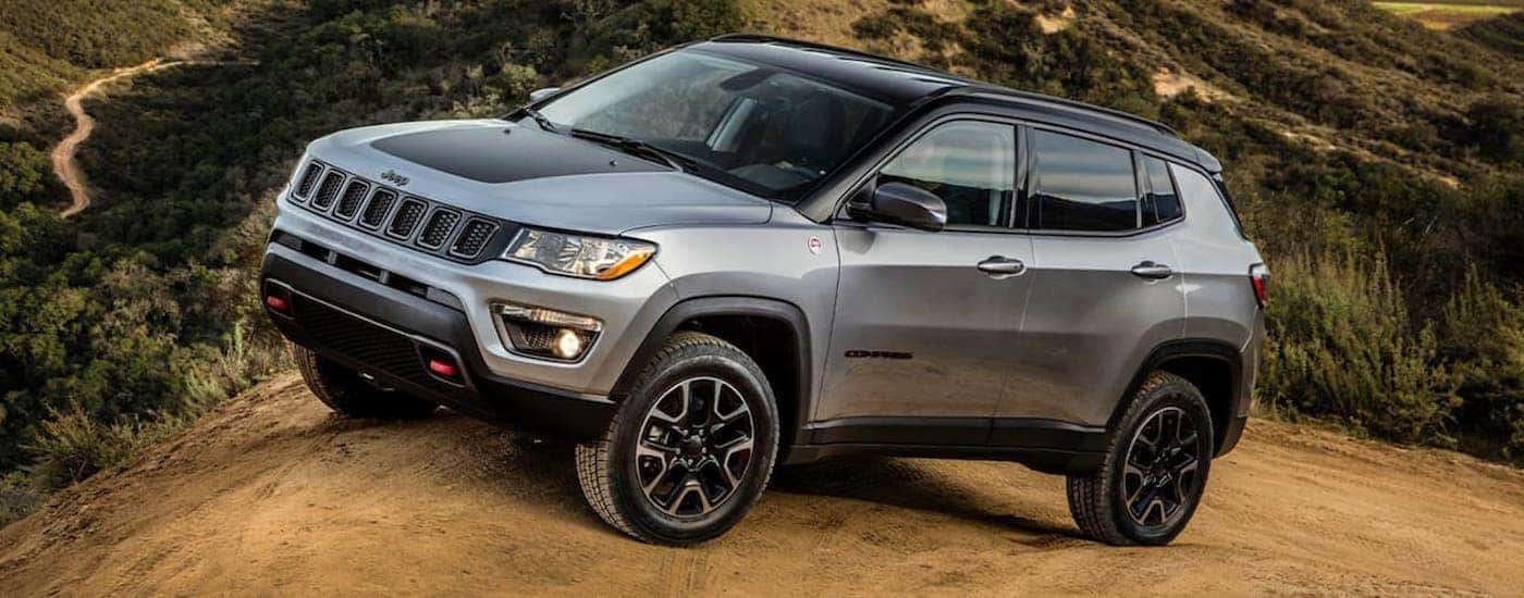 A silver 2020 Jeep Compass Trailhawk is parked in the desert mountains.