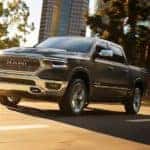 A grey 2019 Ram 1500 is shown driving through a city after looking at a used Ram 1500.