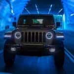 A silver 2021 Jeep Wrangler 4xe is shown from the front driving through a tunnel after leaving an electric SUV dealer.