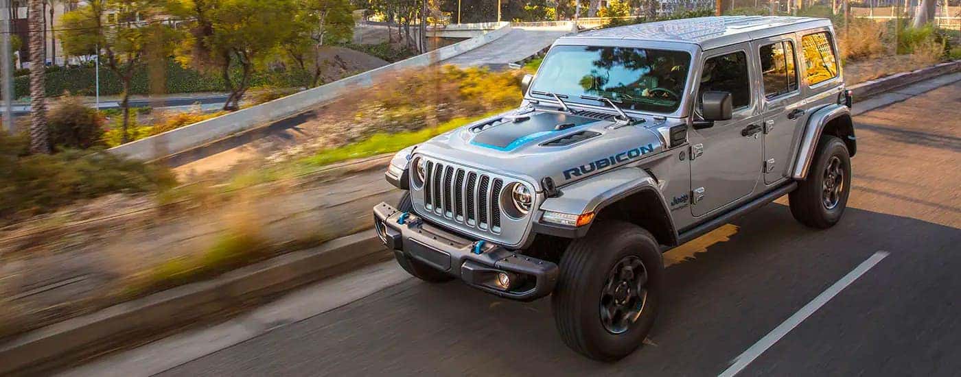 A grey 2021 Jeep Wrangler 4xe is shown driving in a city.