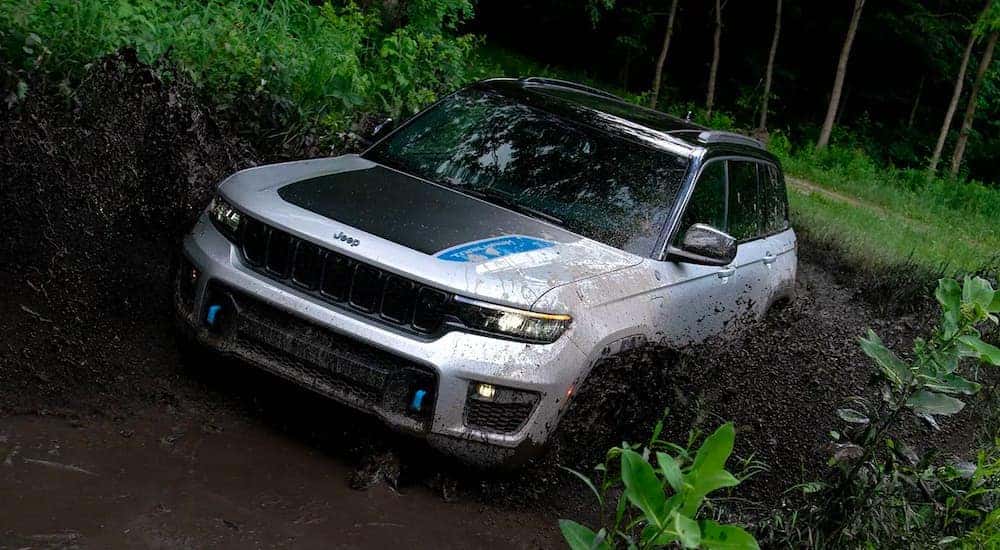 A silver 2022 Jeep Grand Cherokee 4xe is shown driving through a mud puddle after leaving a Jeep Dealership in Los Angeles.