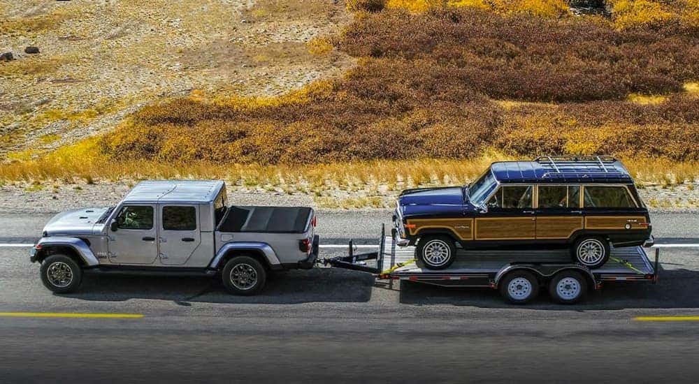 A silver 2021 Jeep Gladiator is shown from the side towing an SJ Wagoneer.