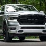 A silver 2020 Ram 1500 is shown parked on a wooded road.