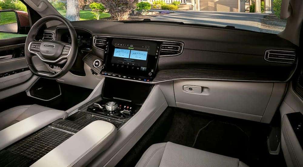 The tan and black interior of a 2022 Wagoneer shows the steering wheel and center console at an LA Wagoneer dealership.