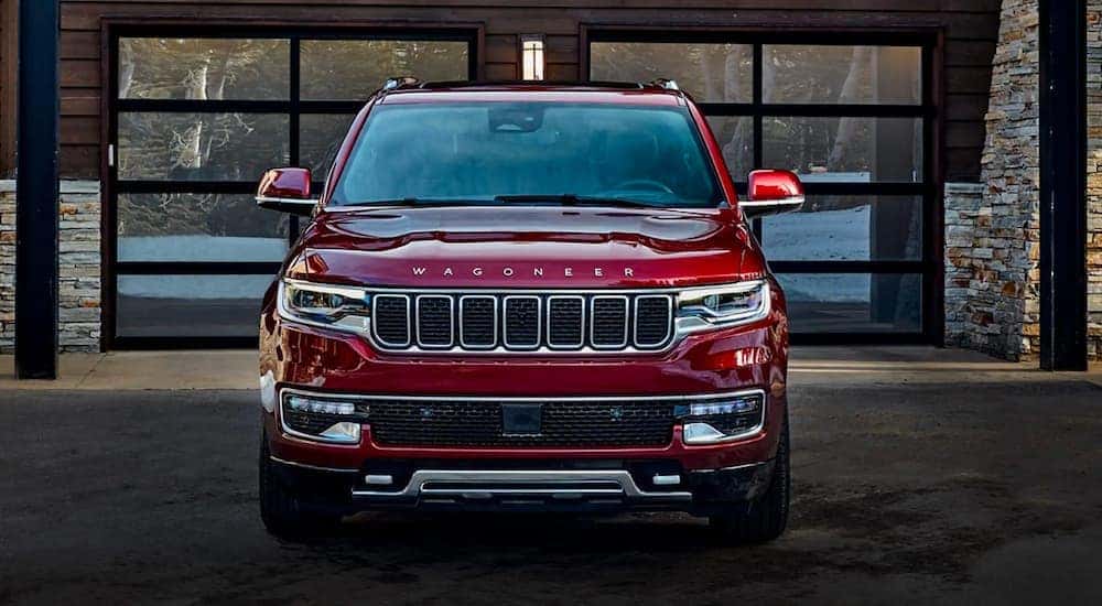A red 2022 Wagoneer is shown from the front parked outside of a modern home.