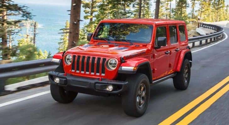 A red 2021 Jeep Wrangler Unlimited is shown from the front driving on an open road after leaving a Southern California Wrangler dealer.