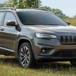 A grey 2020 used Jeep Cherokee is shown parked in a grassy field.