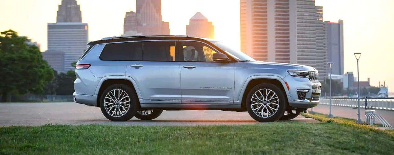 A silver 2022 Jeep Grand Cherokee L is shown parked in a city at sunset.