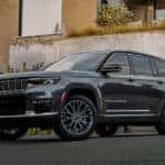 A grey 2022 Jeep Grand Cherokee is shown parked by a concrete wall after leaving a California luxury SUV dealer.