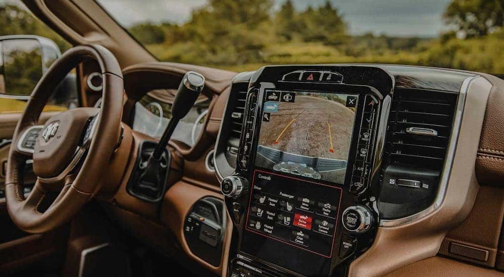 The brown and black interior of a 2022 Ram 3500 shows the steering wheel and infotainment screen.