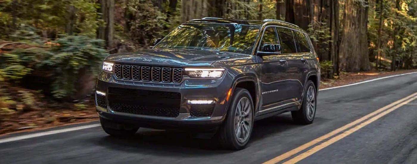 A grey 2021 Jeep Cherokee L is shown from the front driving on an open road after looking at a used Jeep Grand Cherokee.