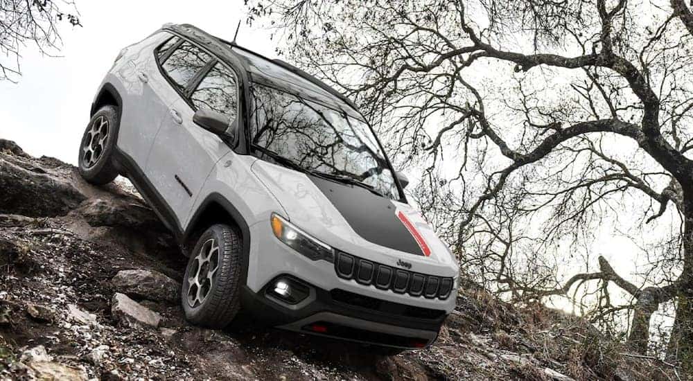A white 2022 Jeep Compass Trailhawk is shown off-roading down a steep trail.