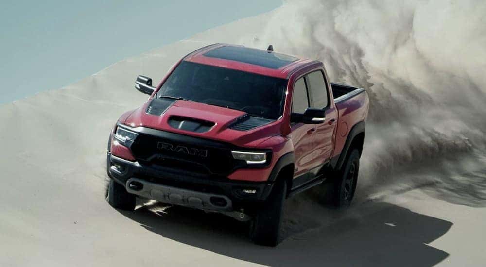 A red 2022 Ram 1500 TRX is shown from the front off-roading in the desert after leaving a Ram dealer near you.