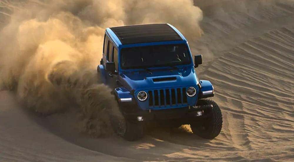 A blue 2021 Jeep Wrangler Rubicon 392 is shown off-roading in the desert after looking at a used Jeep Wrangler’s buyer’s guide.
