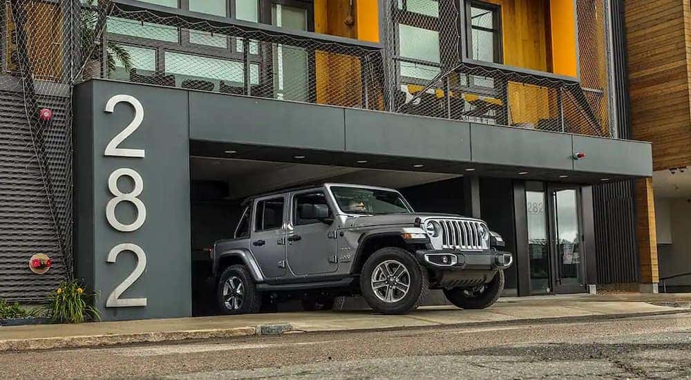 A grey 2020 Jeep Wrangler Sahara Unlimited is shown leaving a parking garage.