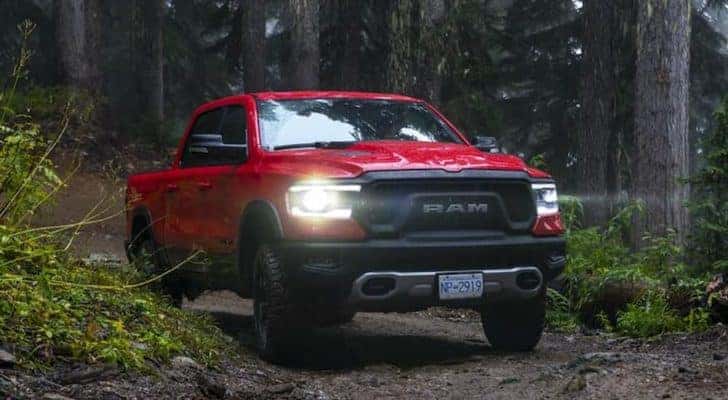A red 2019 Ram 1500 Rebel is shown on a forest trail after leaving a used work truck dealer.