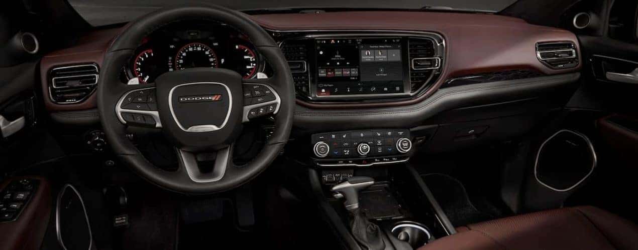 The black and brown interior of a 2022 Dodge Durango shows the steering wheel and infotainment screen.