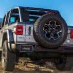 A silver 2022 Jeep Wrangler 4xe is shown from the rear off-roading through the desert.