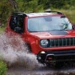 A red 2022 Jeep Renegade is shown from the front off-roading through a river.