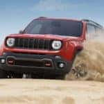 A red 2022 Jeep Renegade is shown from the front off-roading through the desert.
