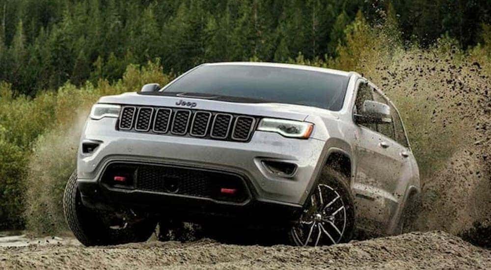 A silver 2019 Jeep Grand Cherokee is shown off-roading.
