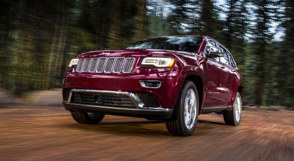 A popular used Jeep Grand Cherokee, a red 2016 Jeep Grand Cherokee is shown driving through a forest.