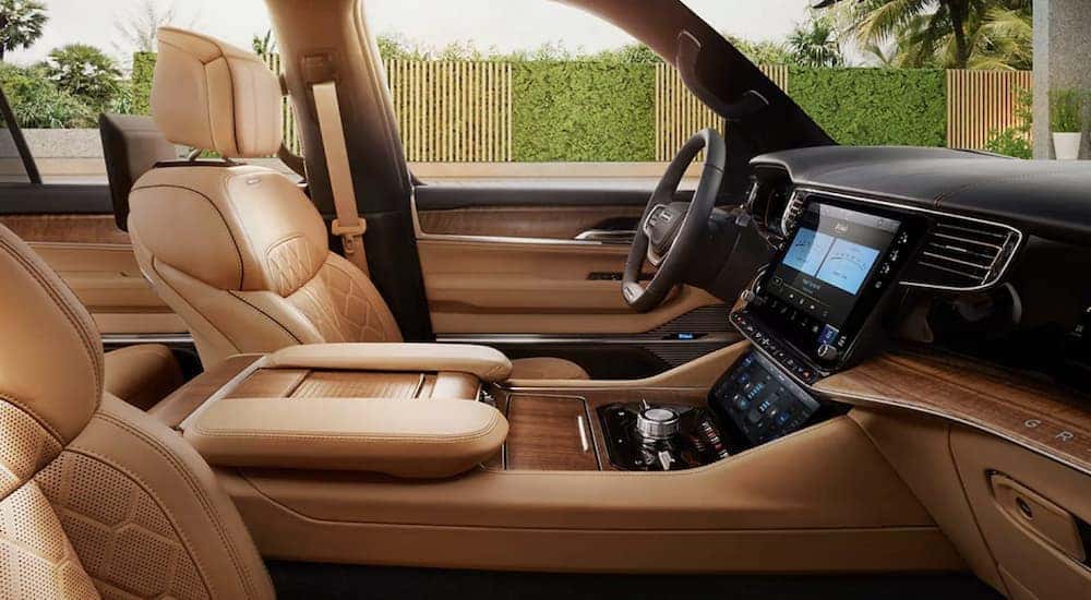 The tan interior of a 2022 Grand Wagoneer shows the front seats and steering wheel.
