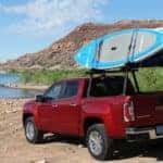 A red 2019 GMC Canyon SLT is shown parked near a body of water with paddle boards.