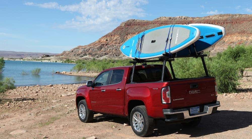 A red 2019 GMC Canyon SLT is shown parked near a body of water with paddle boards.