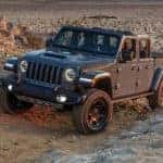 A grey 2021 Jeep Gladiator Mojave is shown from the front while it drives through sand.