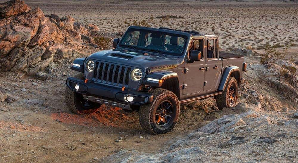 A grey 2021 Jeep Gladiator Mojave is shown from the front at an angle while driving through the desert after leaving a Jeep dealership near you.