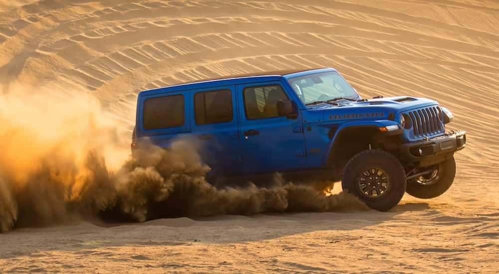 A 2021 Jeep Rubicon 392 is shown from the side while it drives through sand dunes.