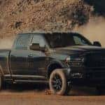 A black 2021 Ram 2500 is shown kicking up dirt off-road.
