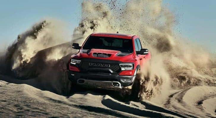 A red 2022 Ram 1500 is shown from the front off-roading in the desert.