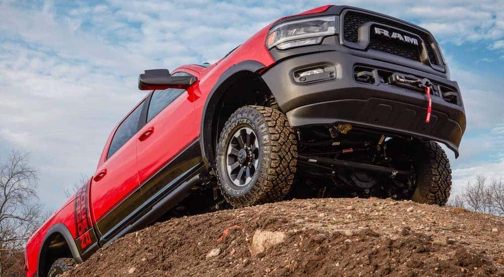 A red 2020 Ram 2500 Power Wagon is shown from the front at a low angle while it climbs over a rock.